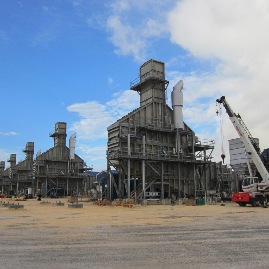 Industrial facility with large metal structures under a partly cloudy sky.
