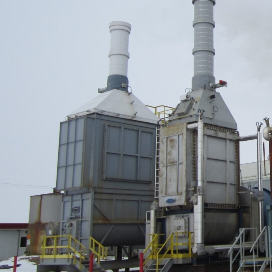 Industrial cooling towers with dual chimneys under a cloudy sky.